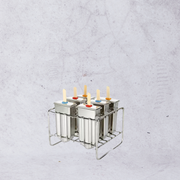 Metallic popsicle mold with colorful sticks on a textured gray background