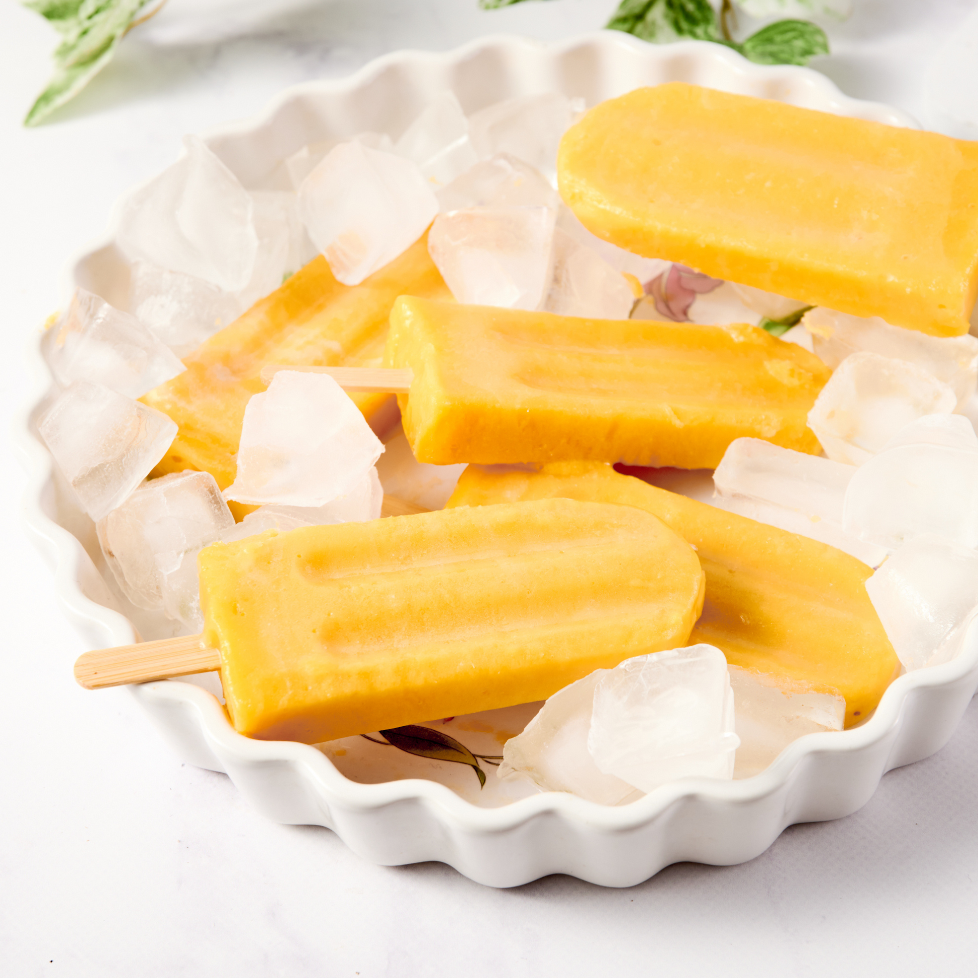 Yellow popsicles in a white decorative bowl on a light background