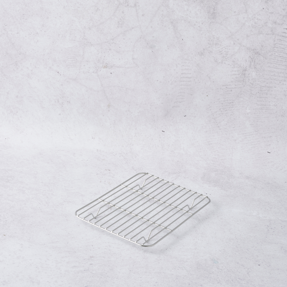 Stainless steel mini cooling rack with grid design, positioned on a light textured background.