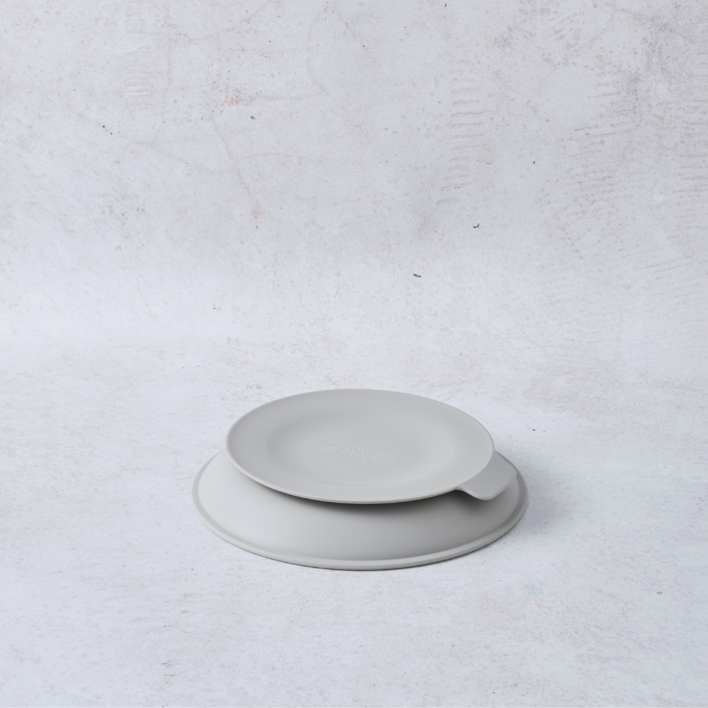 Stainless steel round plate with a suction base, featuring a smooth gray surface and a slight lip for easy handling.